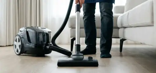 Professional house cleaner vacuuming a living room floor with a canister vacuum cleaner, Toledo, OH.