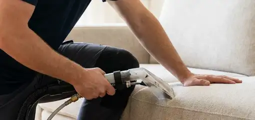 Professional upholstery cleaner deep-cleaning a fabric sofa with a handheld extraction tool, Toledo, OH.